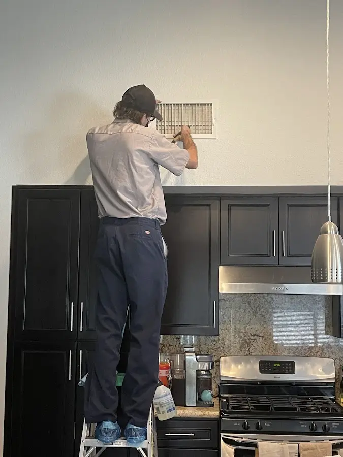 Technician inspecting an air vent during HVAC service in Bonita